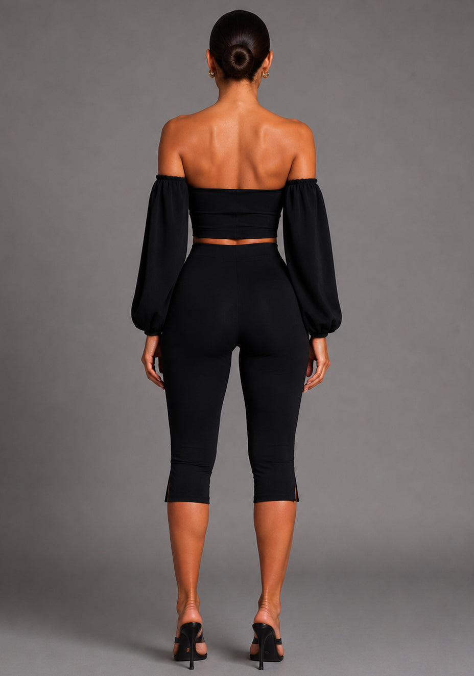 Back image of a model wearing the VSPR Belle Sweetheart Neckline Puff Sleeve Black Top featuring dramatic sleeve detailing, a sleek fitted design, and a polished silhouette, posed against a grey studio backdrop.