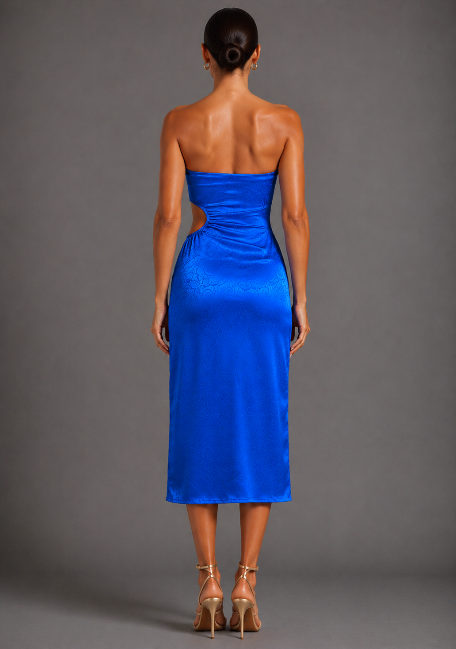 Back image of a model wearing the VSPR Eaden Bandeau Cut Out Cobalt Midaxi Dress, showing the clean strapless silhouette, elegant midaxi length, and smooth satin drape against a grey studio backdrop.