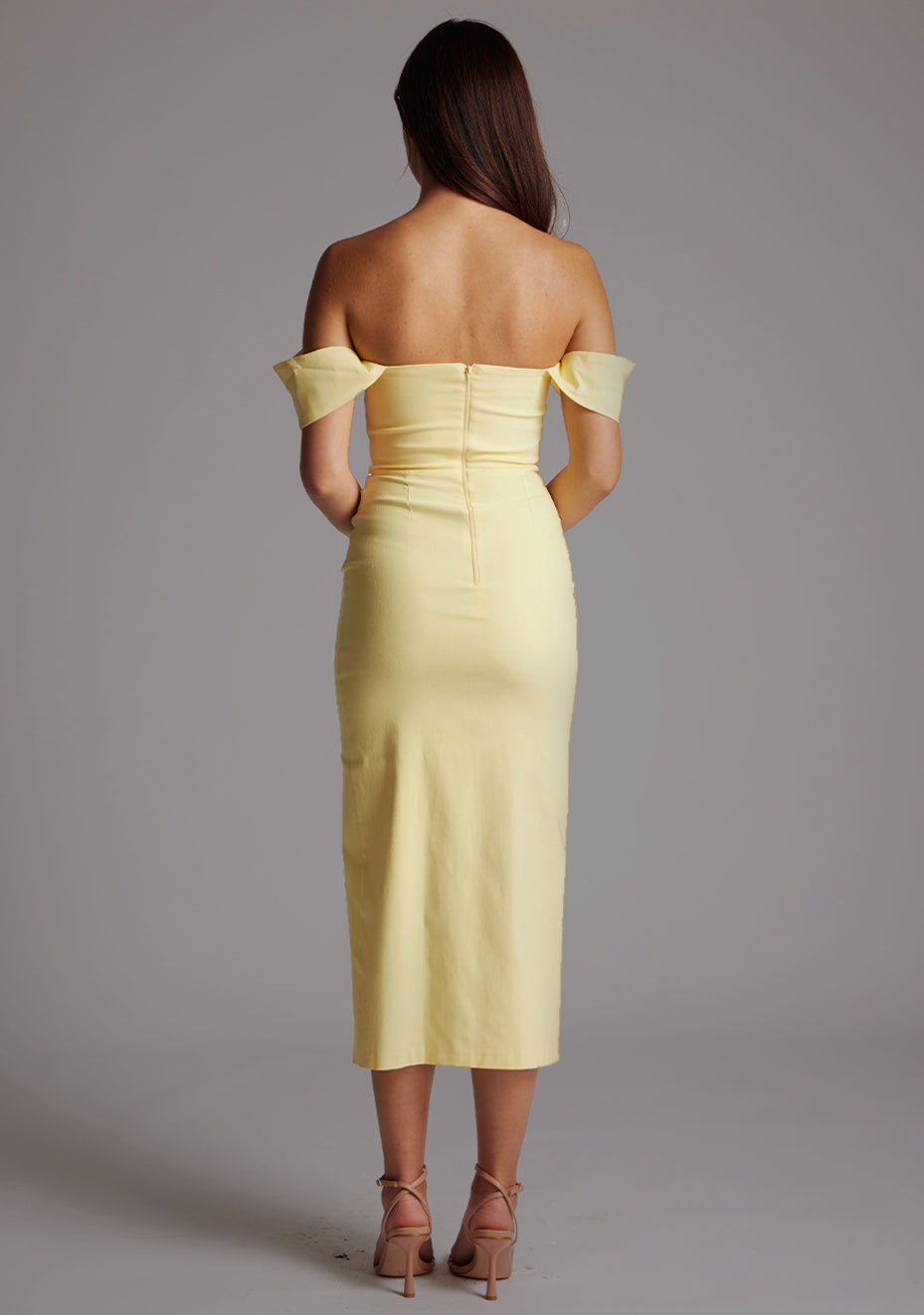 Back image of a model wearing the VSPR Astra Bardot Lemon Midaxi Dress, emphasizing the sculpted fit, clean lines, and graceful midaxi length against a grey studio backdrop.