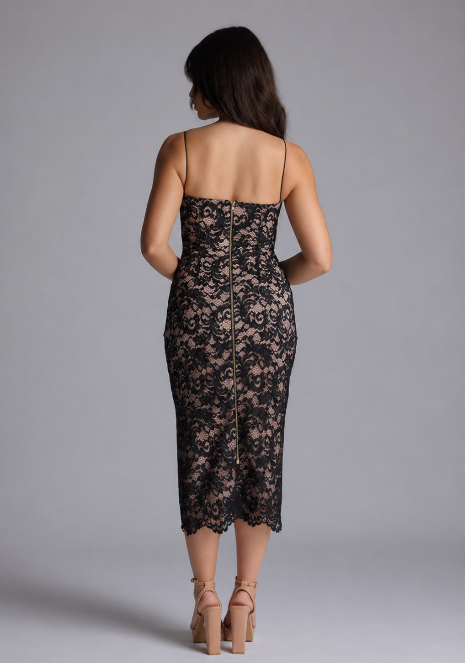 Back image of a model wearing the VSPR Arden Petite Bodycon Black Lace Midaxi Dress, featuring the elegant lace overlay, thin straps, and gold centre-back zip against a grey studio backdrop.