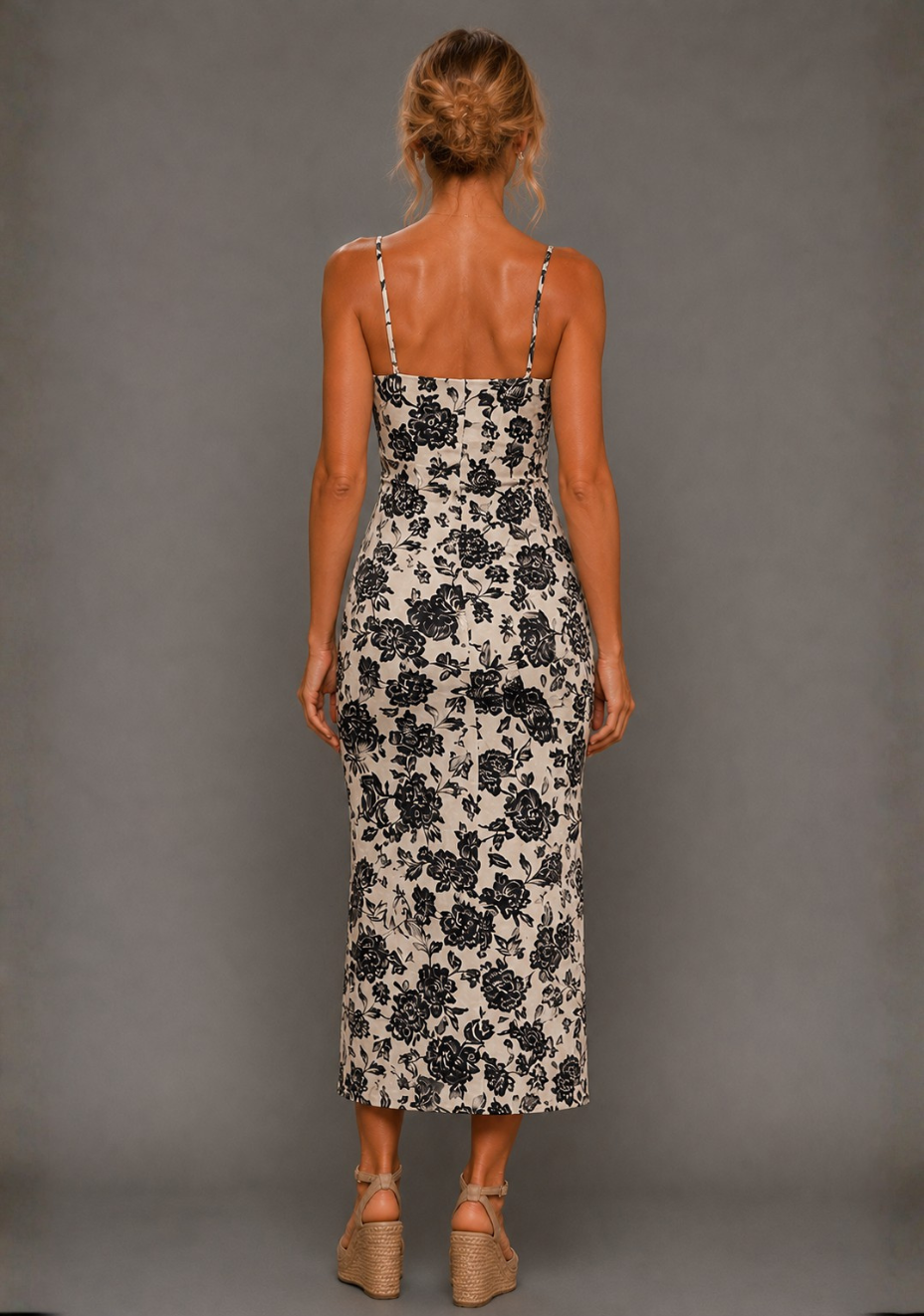 Back image of a model wearing the VSPR Cora Square Neck Champagne Midaxi Dress, showing the sleek back detailing and elongated midaxi hemline with a subtle split, standing against a grey studio backdrop.
