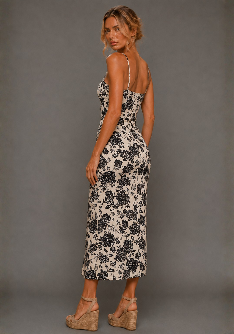 Side back image of a model wearing the VSPR Cora Square Neck Champagne Midaxi Dress, highlighting the subtle back split and the fitted silhouette through the hips, standing against a grey studio backdrop.