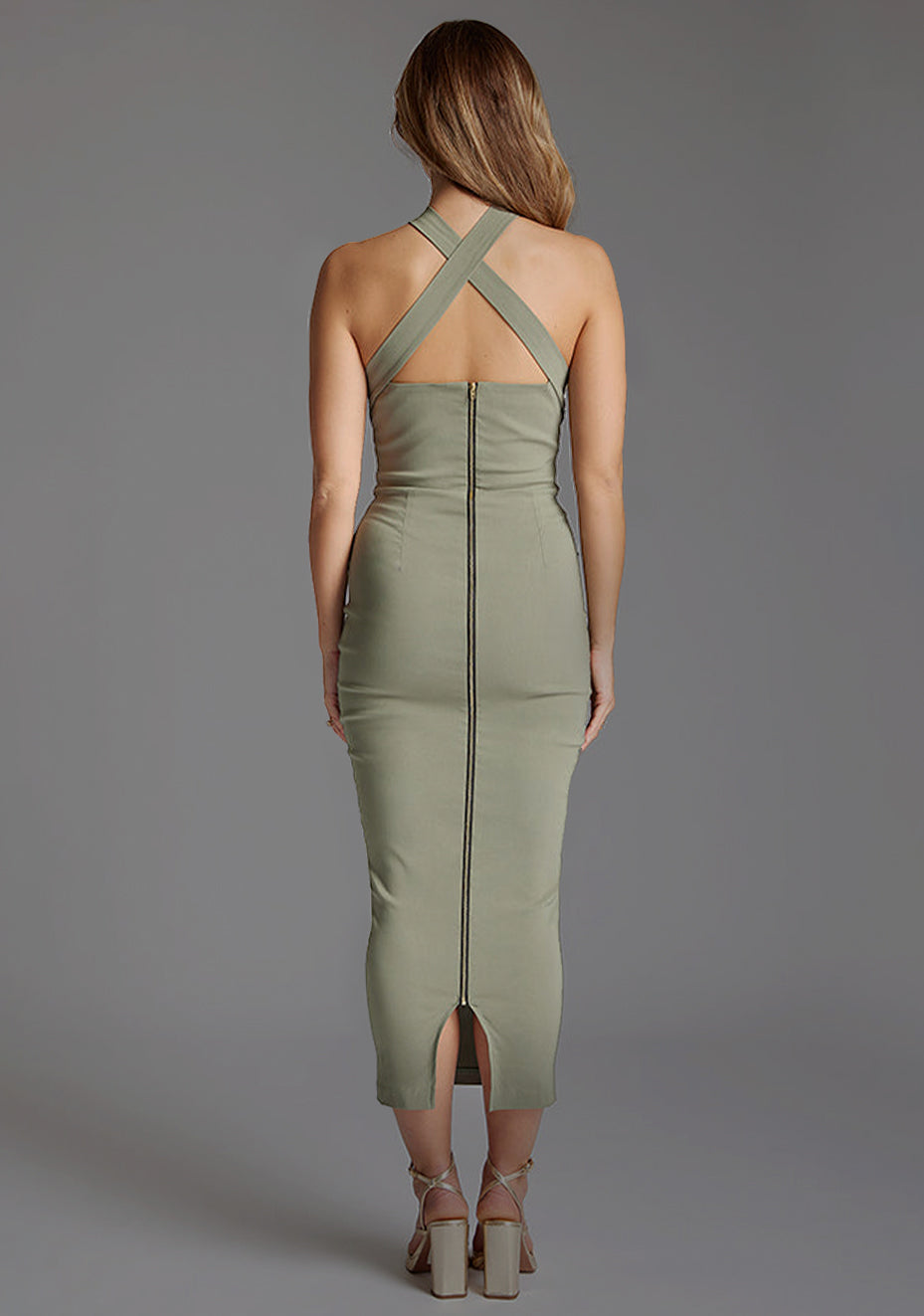 Back image of a model wearing the VSPR Jemma Halter Neck Olive Midaxi Dress from the back, featuring the sophisticated criss-cross design and sleek gold zip detail.