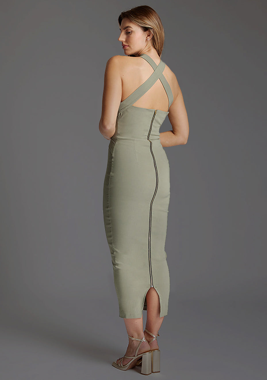 Side back image of a model wearing the VSPR Jemma Halter Neck Olive Midaxi Dress, showcasing the intricate criss-cross back design, centre back gold zip and sculpted silhouette.