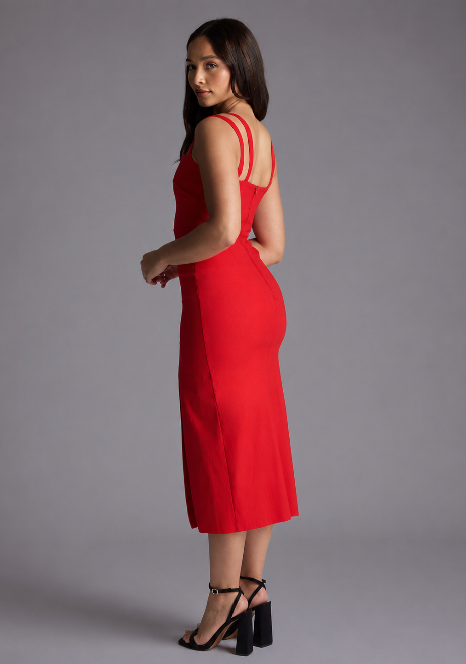 Woman wearing the Vesper Petite Violet red sweetheart neckline midaxi dress against a grey background, side back view