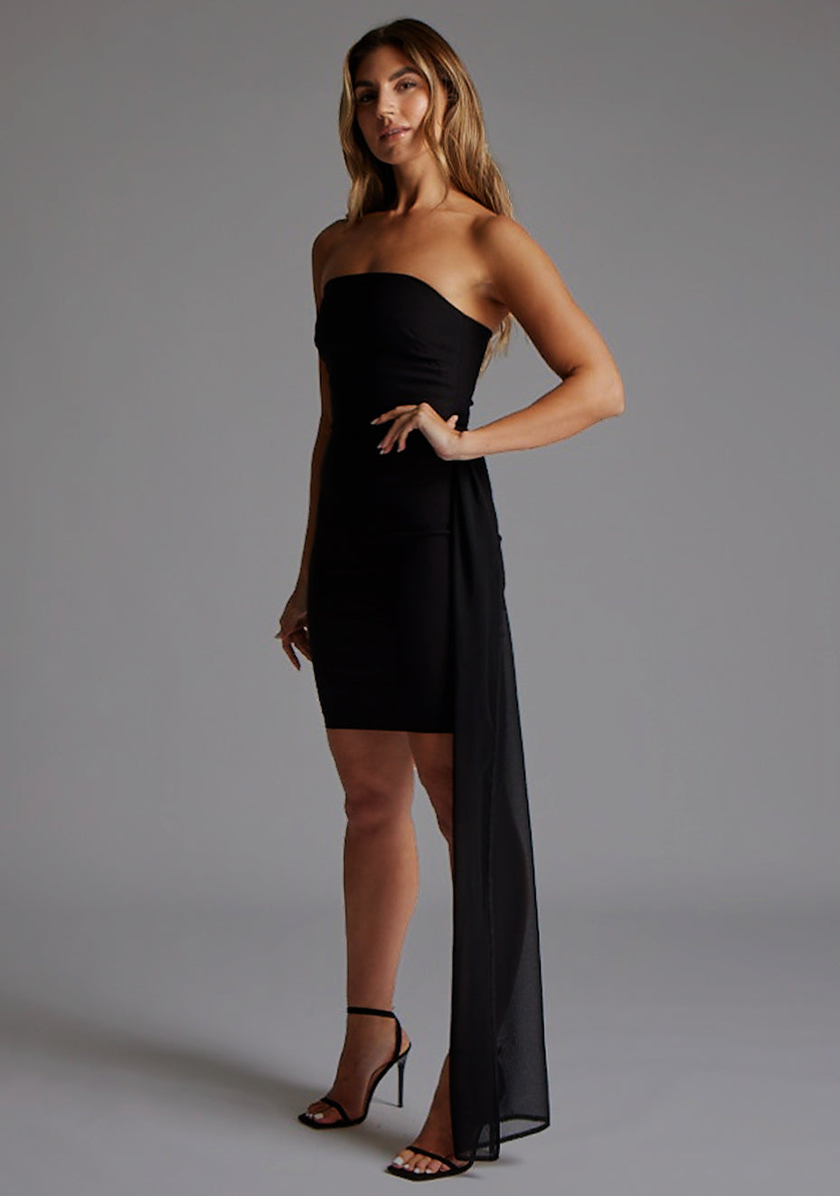 Side front view of a model wearing the Vesper Belisse Strapless Mini Dress in Black highlighting soft draping and a streamlined strapless design.