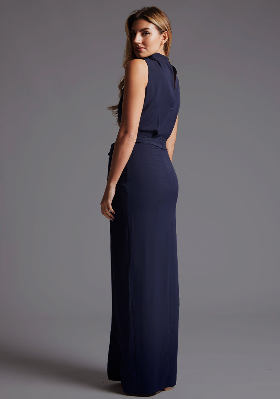 Side back image of a model wearing the Vesper Chrysta High Neck Maxi Dress in Navy, highlighting the smooth back line and streamlined silhouette.