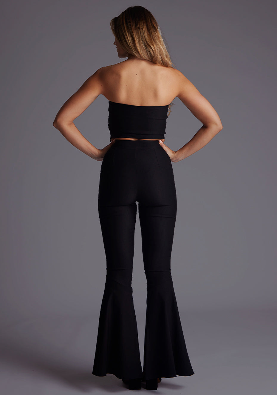 Back image of a model wearing the Vesper Flavia Strapless Crop Top in Black, emphasizing the smooth strapless construction and clean, modern finish.