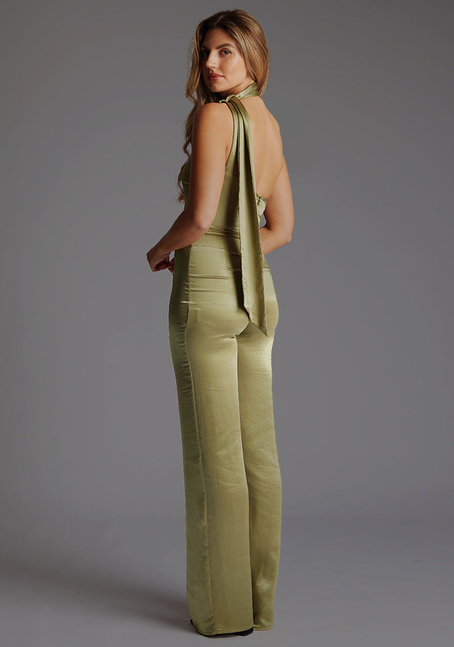 Side-back image of a model wearing the VSPR Juniper Halter Pine Green High-Neck Top, highlighting the back profile and sophisticated halter construction.