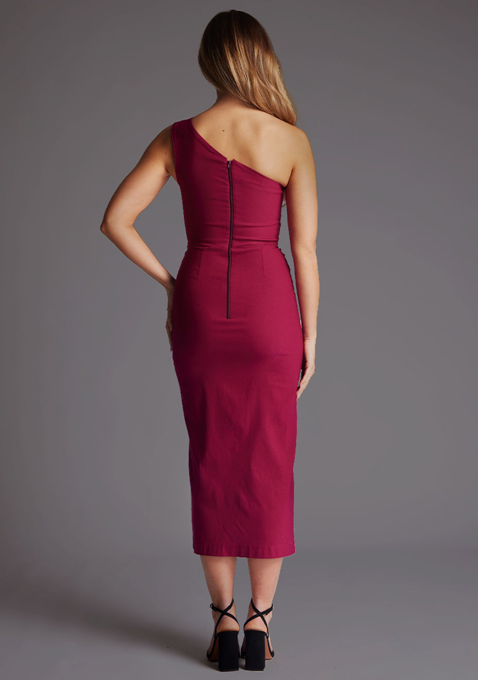 Back image of a model wearing a Marsha Berry One Shoulder Midaxi Dress with a asymmetric neckline, one shoulder detail and front skirt split. The design featured is the Vesper Marsha Berry One shoulder Midaxi Dress.