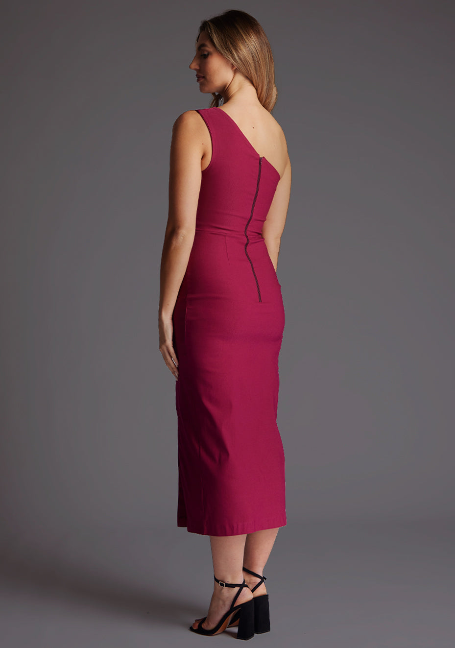 Back  quarter image of a model wearing a Marsha Berry One Shoulder Midaxi Dress with a asymmetric neckline, one shoulder detail and front skirt split. The design featured is the Vesper Marsha Berry One shoulder Midaxi Dress.